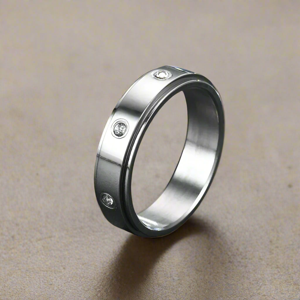 Silver fidget ring smooth band with embedded rhinestones on a light surface