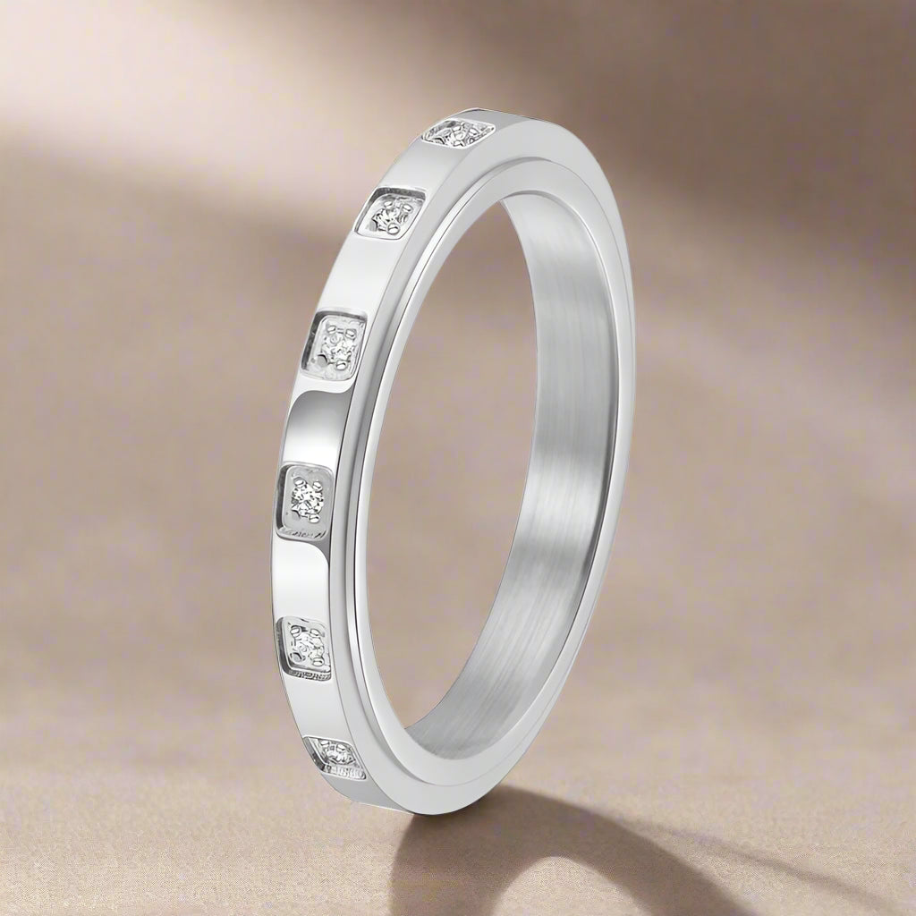Silver ring with embedded stones on a light background